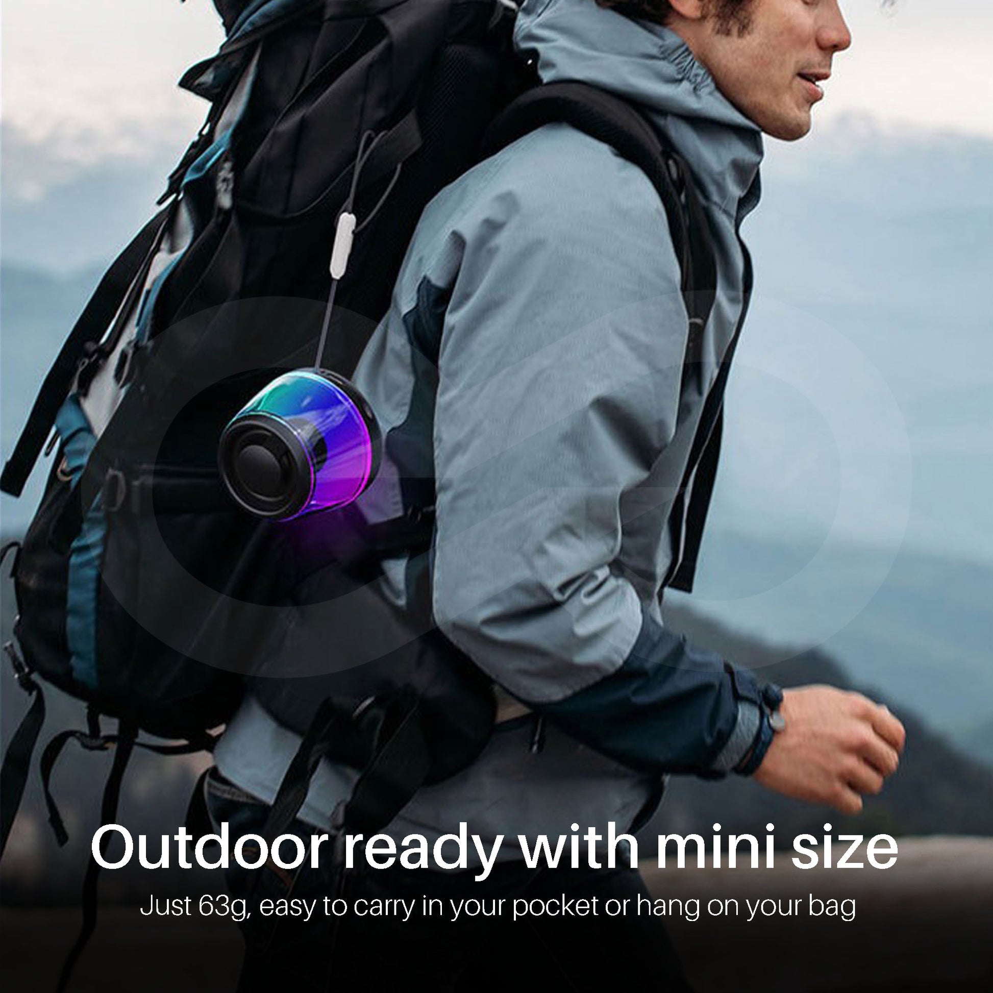 Person with a backpack featuring a portable device, set against a mountainous landscape.