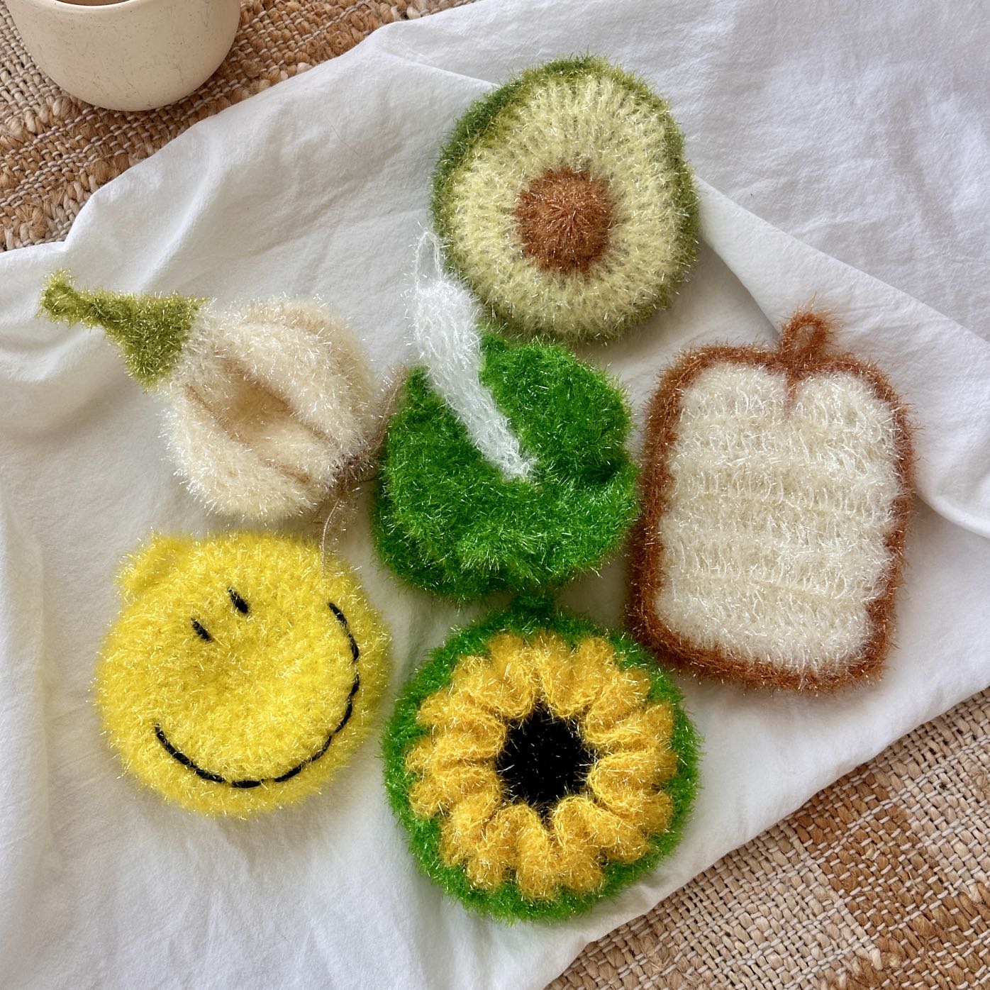 Set of hand-knitted dish scrubbers on a white fabric background