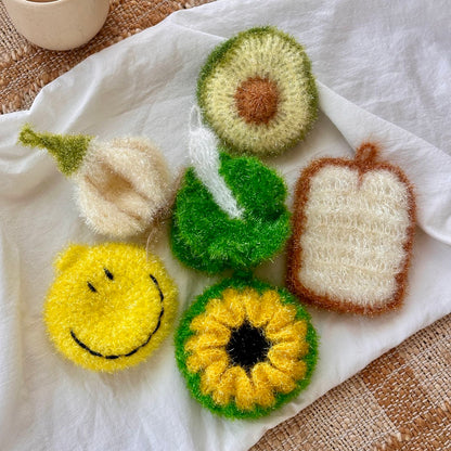 Set of hand-knitted dish scrubbers on a white fabric background